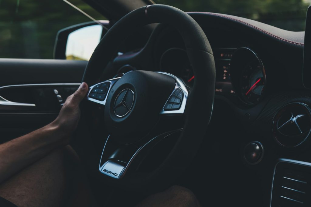 person holding on black steering wheel inside car