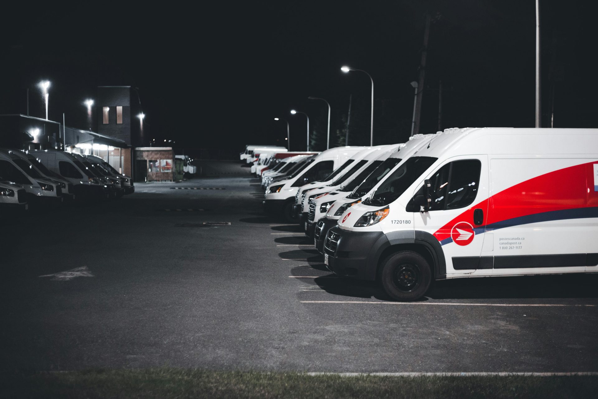 Series of White Vans Parked on Parking Lot at Night